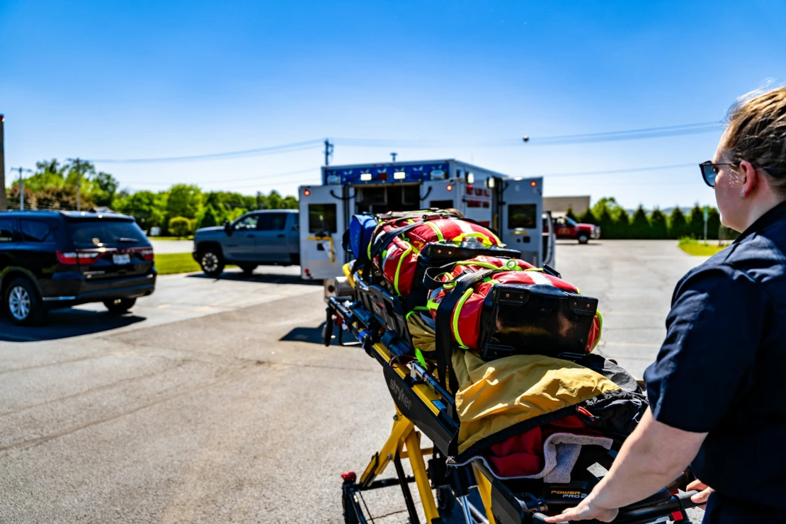 Emt pushing a stretcher towards an ambulance.